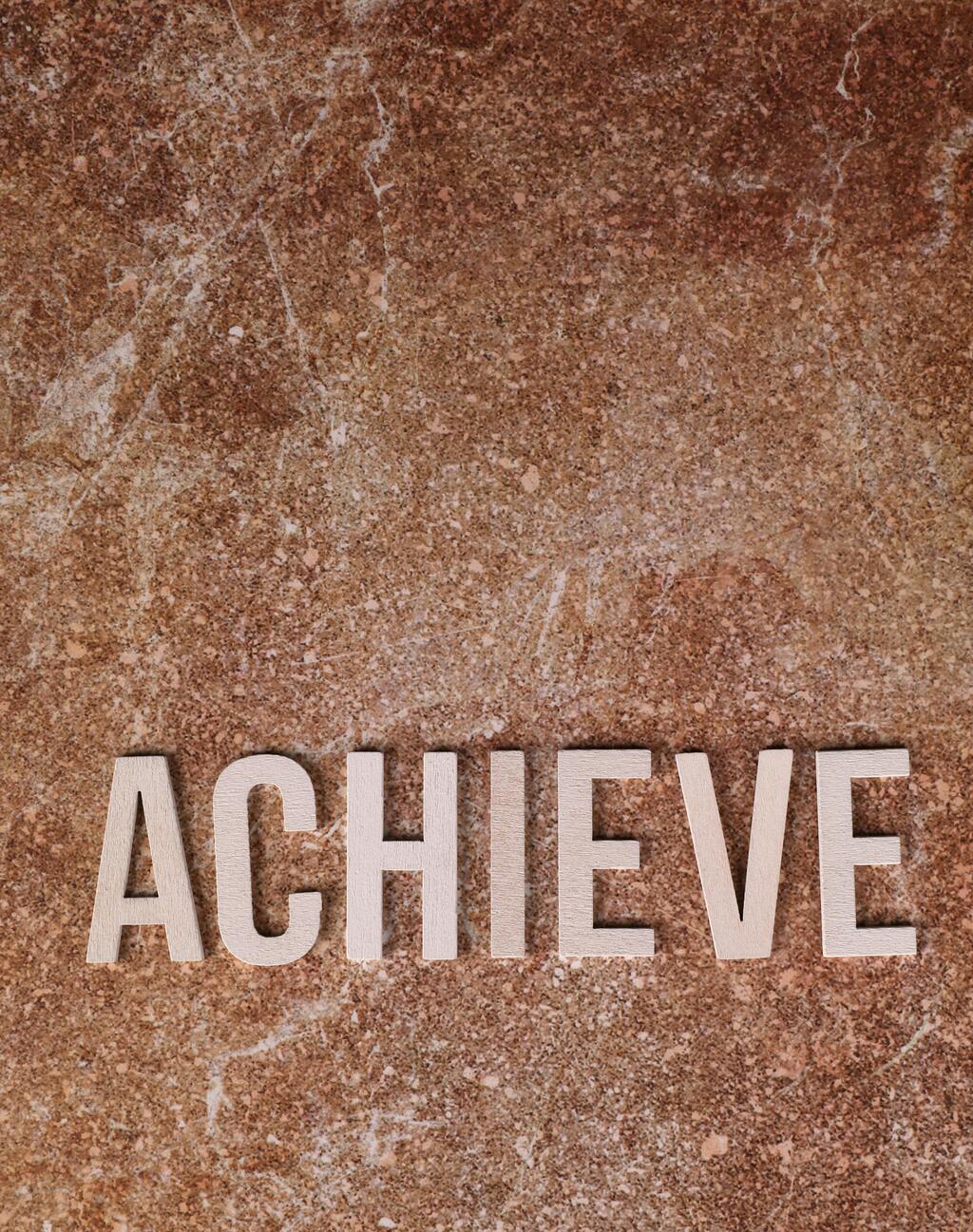 An earth tone marbled background with the word "achieve" in all capital letters.